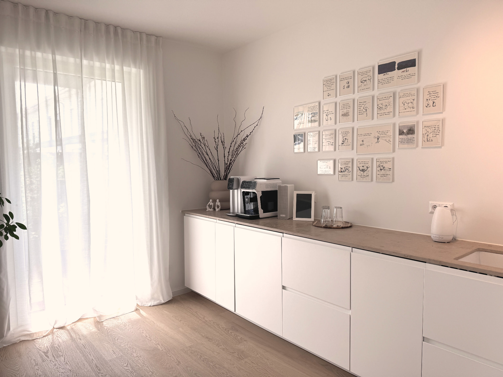 Küchen- und Wartebereich der Praxis in Hanau mit heller Einbauzeile und Bilderwand