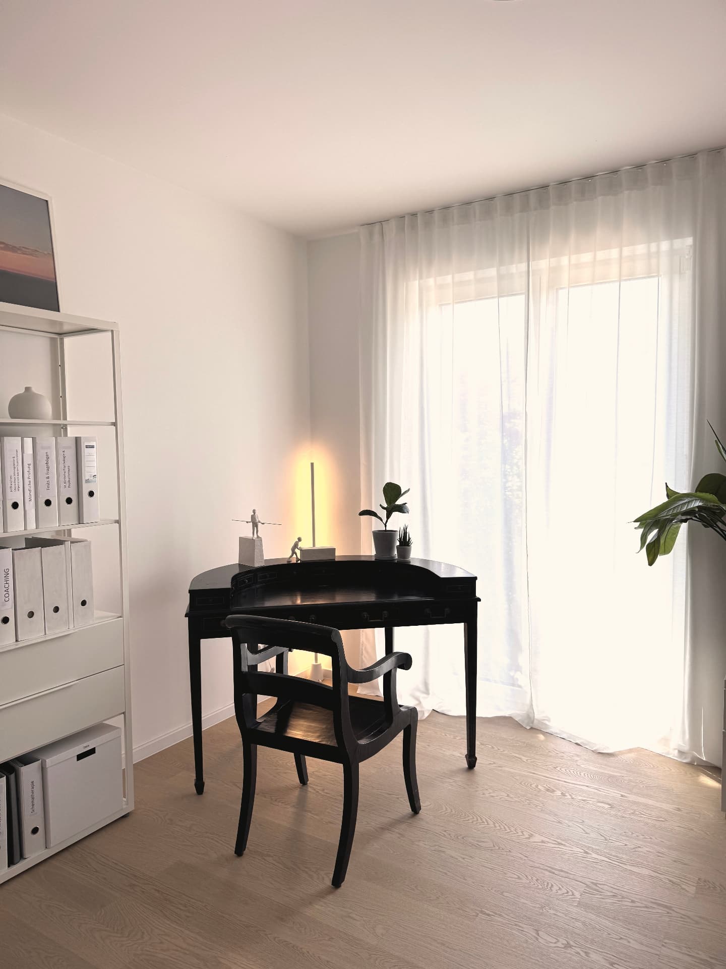 Schreibtischplatz der Praxis mit antikem schwarzem Sekretär und viel Tageslicht
