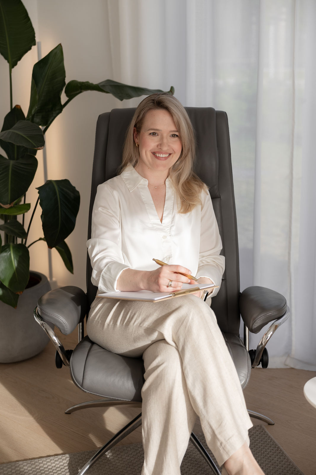 Jana Stenzel in einem hellen Therapieraum mit Notizblock und Stift